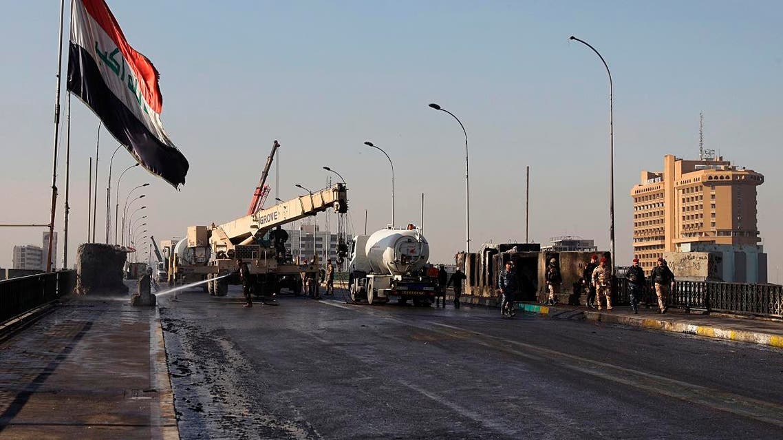After pushing out anti-government protesters from the area, municipal workers clean while security forces remove concrete walls in preparations to re-open Sinak Bridge. (AP)