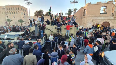 People stand and sit with Libyan national flags above armoured military vehicles of forces loyal to the UN-recognised Tripoli-based "Government of National Accord" (GNA) during a celebration in the capital's Martyrs' Square on January 31, 2020. (AP)