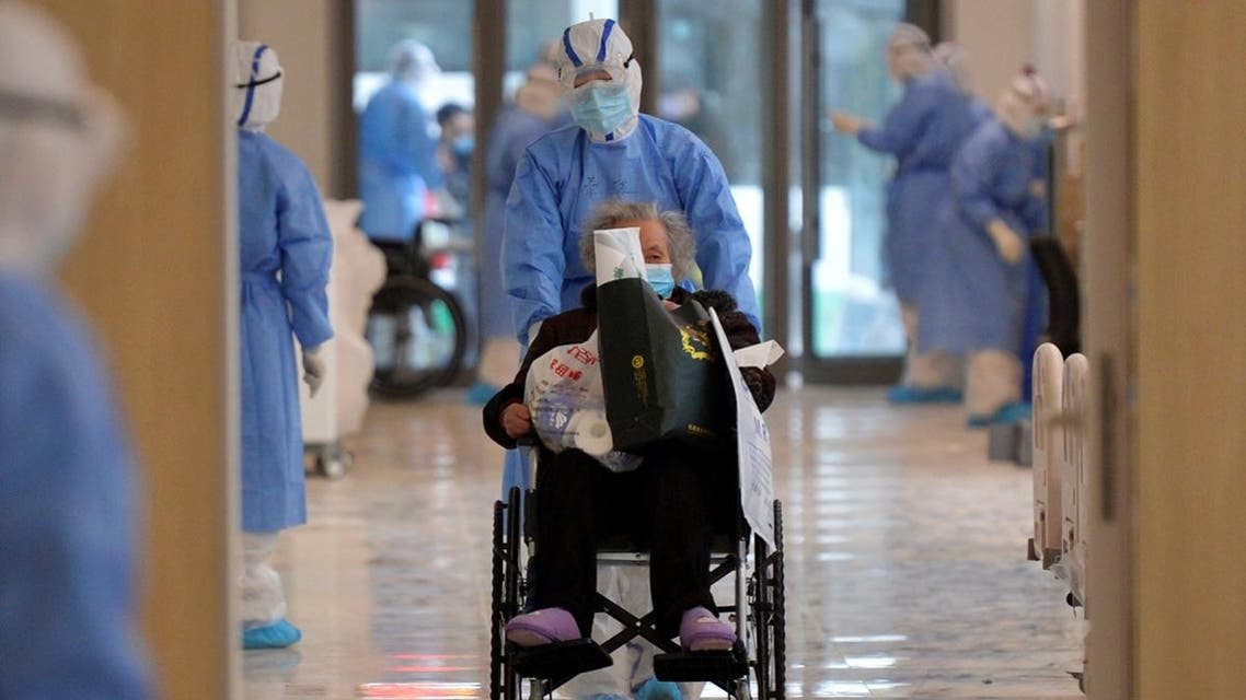 Medical worker in protective suit moves a novel coronavirus patient in a wheelchair at a hospital in Wuhan. (China Daily via Reuters)