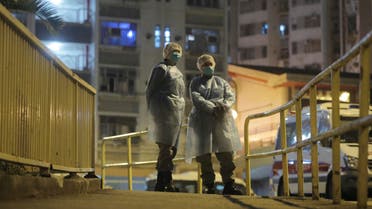 People wearing protective suits stand near the Cheung Hong Estate, a public housing estate, during evacuation of residents in Hong Kong, Tuesday, Feb. 11, 2020. (AP)