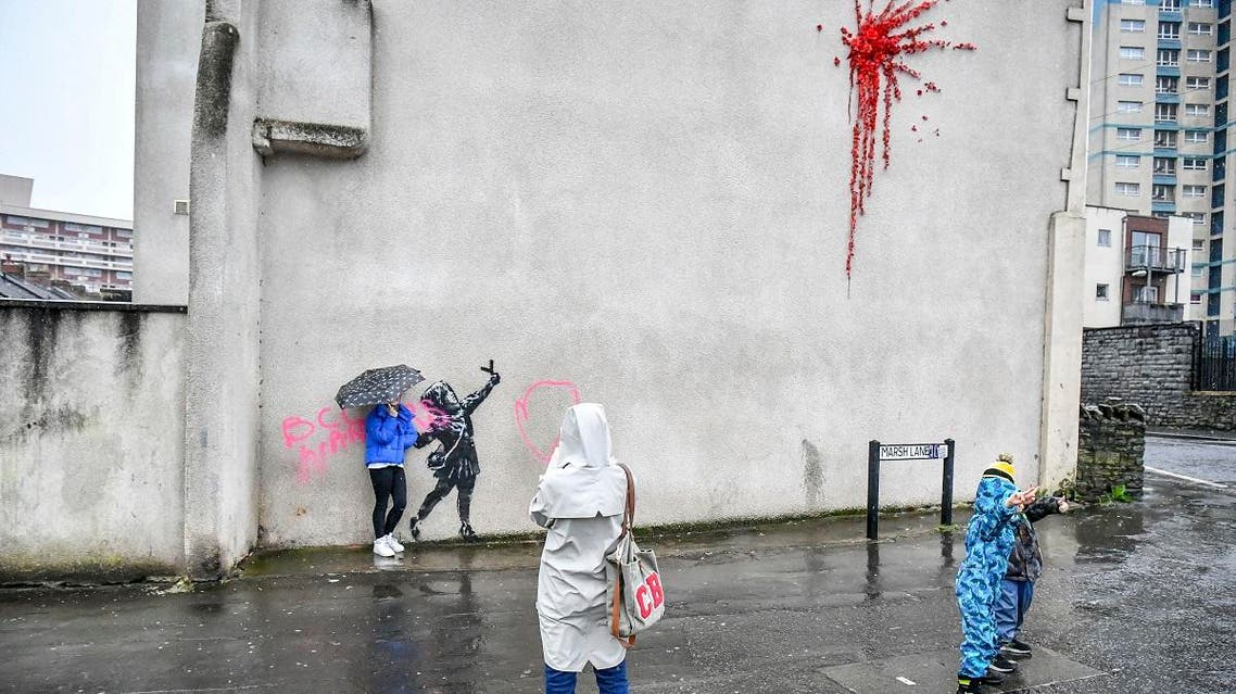 People take photos of a mural by Bansky which has been vandalised, on the side of a house on Marsh Lane, in Barton Hill, Bristol, England, Saturday, Feb. 15, 2020. (AFP)