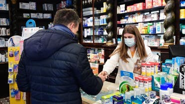 A pharmacist wearing a protective respiratory mask tends to a customer in Codogno, southeast of Milan, on February 22, 2020. afp