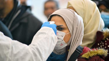 The body temperature of an Iraqi woman returning from Iran is measured upon her arrival at the Najaf International Airport on February 21, 2020, after Iran announced cases of coronavirus infections in the Islamic republic. (AFP)