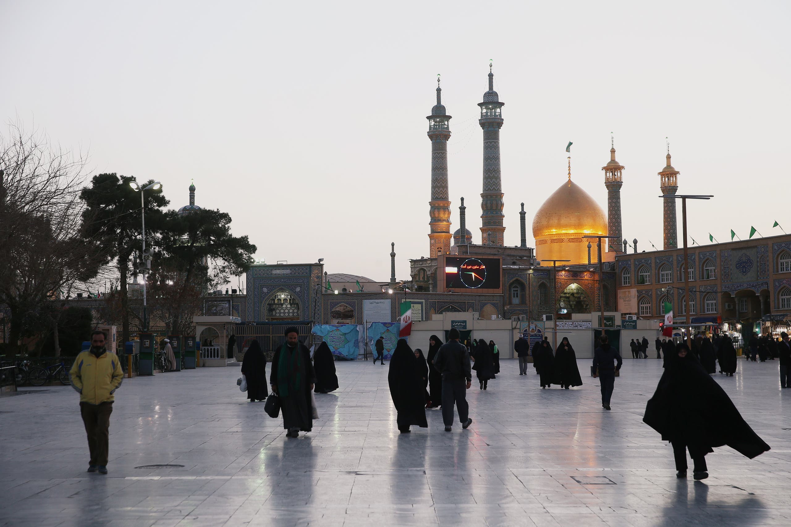 People walk in front of the Shrine of Fatima Masumeh in the city of Qom in Iran (Reuters)