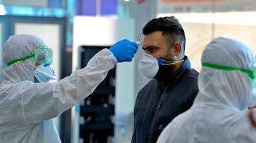 In this Friday, Feb. 21, 2020, file photo, medical staff check passengers arriving from Iran in the airport in Najaf, Iraq. Coronavirus-infected travelers from Iran already have been discovered in Lebanon and Canada. (AP Photo/Anmar Khalil, File)