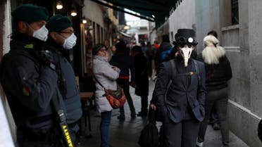 Security personnel wearing protective masks stand next to carnival revelers at Venice Carnival, which the last two days of, as well as Sunday night's festivities, have been cancelled because of an outbreak of coronavirus. (Reuters) 