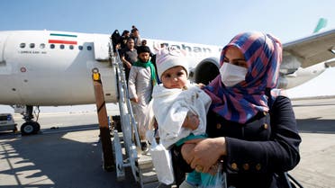 Passengers wearing protective masks disembark from a plane upon their arrival at Najaf airport, amid the new coronavirus outbreak, Iraq. (Reuters)