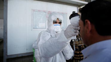 A member of the medical team checks the temperature of an Iraqi man, following the coronavirus outbreak, at the entrance checkpoint of South Mosul, Iraq, February 26, 2020. (Reuters)