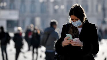 A woman wearing a sanitary mask looks at her phone in Milan on Feb. 24, 2020.  (AP)