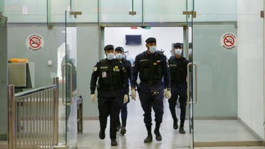 Kuwaiti policemen wearing protective masks wait at Sheikh Saad Airport in Kuwait City, on February 22, 2020, before transferring Kuwaitis arriving from Iran to a hospital to be tested for coronavirus. (AFP)