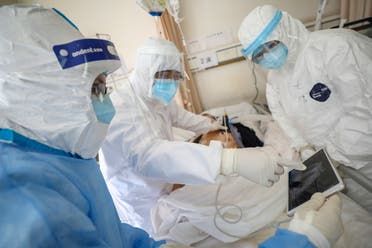 عاملون بالمجال الطبي يرتدون بدل وقائية يعالجون مريضا داخل جناح عزل في مستشفى بووهان ( فبراير  2020- رويترز)