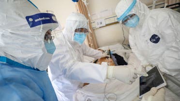 عاملون بالمجال الطبي يرتدون بدل وقائية يعالجون مريضا داخل جناح عزل في مستشفى بووهان ( فبراير  2020- رويترز)