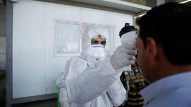 عضو في فريق طبي يفحص درجة حرارة مواطن عند نقطة فحص في جنوب الموصل0 رويترز.)