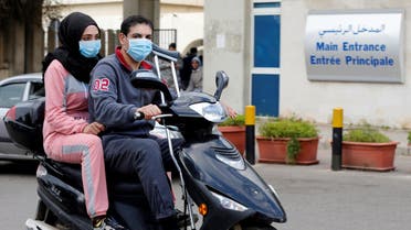 People wearing face masks ride on a motorbike outside Rafik Hariri hospital, where Lebanon's first coronavirus case is being quarantined, in Beirut. (AP)