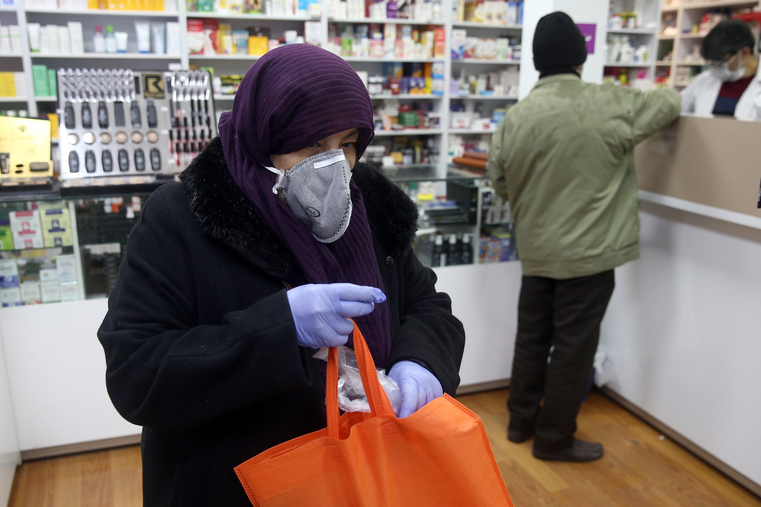 إيرانية ترتدي كمامة وفاذات طبية في صيدلية في طهران خشية من كورونا