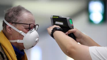 A passenger arriving into Hong Kong International Airport gets his temperature checked by a worker using an infrared thermometer, following the coronavirus outbreak in Hong Kong. (Reuters)