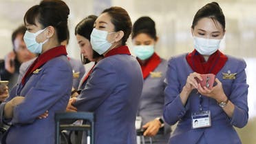 A flight crew from China Airlines, wearing protective masks, stand in the international terminal after arriving on a flight from Taipei at Los Angeles International Airport (LAX) on February 28, 2020 in Los Angeles, California. (AFP)