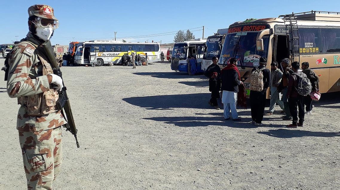 A soldier (L) wears a face mask as pilgrims leave after completing their quarantine period following their return from Iran via the Pakistan-Iran border town of Taftan on February 29, 2020. (AFP)