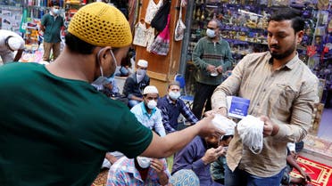 A vendor distributes protective face masks following the coronavirus outbreak, as people pray on a street during Friday prayers in local souq, in Manama, Bahrain, February 28, 2020. (Reuters)
