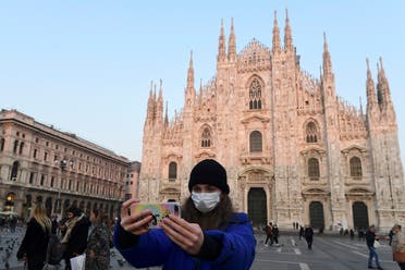 A woman wearing a protective facemask takes a selfie picture in the Piazza del Duomo in central Milan, on February 24, 2020. (AFP)