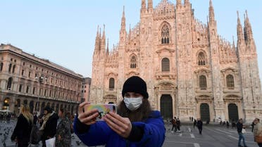 A woman wearing a protective facemask takes a selfie picture in the Piazza del Duomo in central Milan, on February 24, 2020. (AFP)