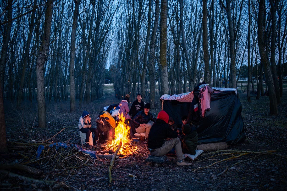 A group of migrants rest at a fire as they wait to cross the Maritsa river to reach Greece at the Turkish-Greek border, in Edirne, in northwestern Turkey, on March 1, 2020. (AFP)