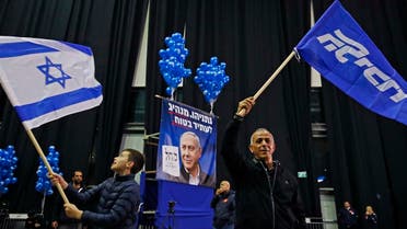 A man waves a Likud party flag while another youth waves an Israeli flag, at the Likud's electoral headquarters in the coastal city of Tel Aviv on March 2, 2020, after polls officially closed. (AFP)