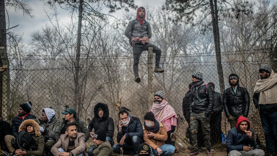 Migrants sit waiting near the buffer zone at Turkey-Greece border, at Pazarkule, in Edirne district. (AFP)