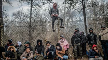 Migrants sit waiting near the buffer zone at Turkey-Greece border, at Pazarkule, in Edirne district. (AFP)
