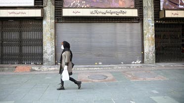 An Iranian woman wears a protective mask to prevent contracting coronavirus, as she walks on a street in front of a closed cinema in Tehran. (Reuters)