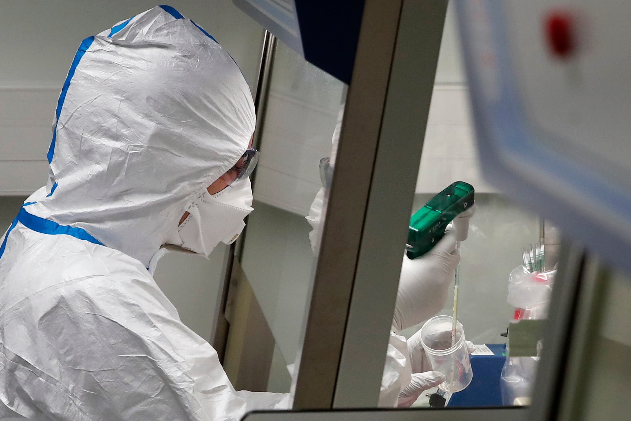 French lab scientist in hazmat gear inserting liquid in test tube manipulates potentially infected patient samples at Pasteur Institute in Paris on Feb. 6, 2020. (AP)