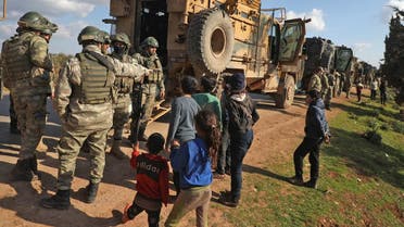 Displaced Syrian children speak with Turkish soldiers as their convoy is parked near the town of Batabu on the highway linking Idlib to the Syrian Bab al-Hawa border crossing with Turkey, on March 2, 2020. (AFP)