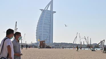 Tourists wearing surgical masks are pictured on a beach next to Burj Al Arab in Dubai on January 29 2020. (AFP)