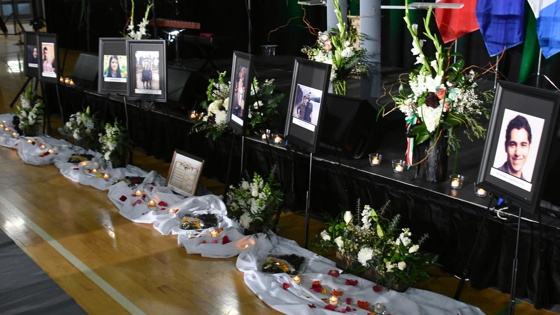 Mourners place flowers by photos of the victims in front of the stage before the start of a memorial service for the Ukrainian Airlines flight PS752 who crashed in Iran at the Saville Community Sports Centre in Edmonton, Canada on January 12, 2020.