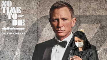 A woman wearing a facemask amid fears of the spread of the novel coronavirus walks past a poster for the new James Bond movie “No Time to Die” in Bangkok. (AFP)