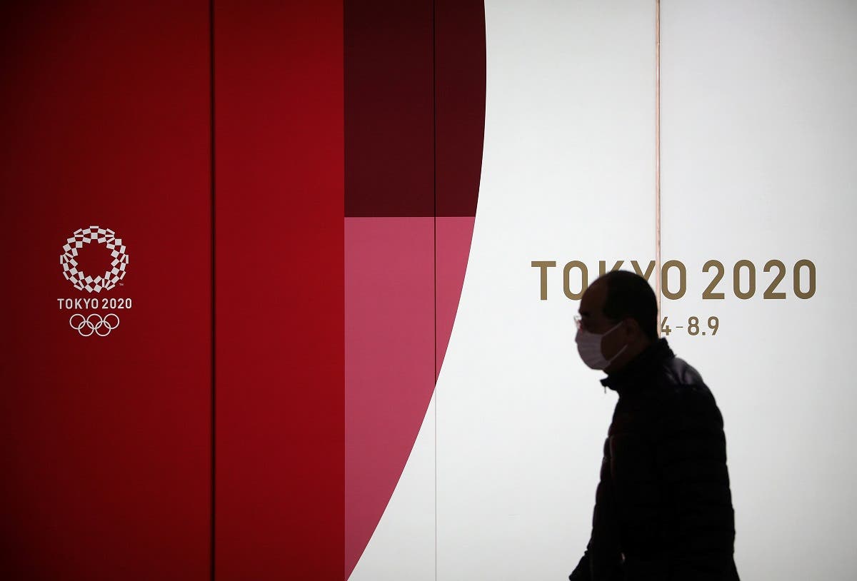 A man wearing a protective face mask walks past an advertising billboard of Tokyo Olympics 2020, near the Shinjuku station in Tokyo, Japan, March 3, 2020. (Reuters)