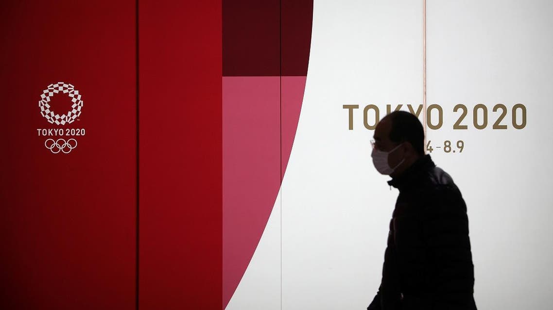 A man wearing a protective face mask walks past an advertising billboard of Tokyo Olympics 2020, near the Shinjuku station in Tokyo, Japan, March 3, 2020. (Reuters)
