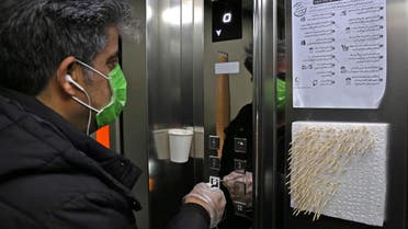 An Iranian man uses small sticks to push the elevator button at an office building in Tehran AFP
