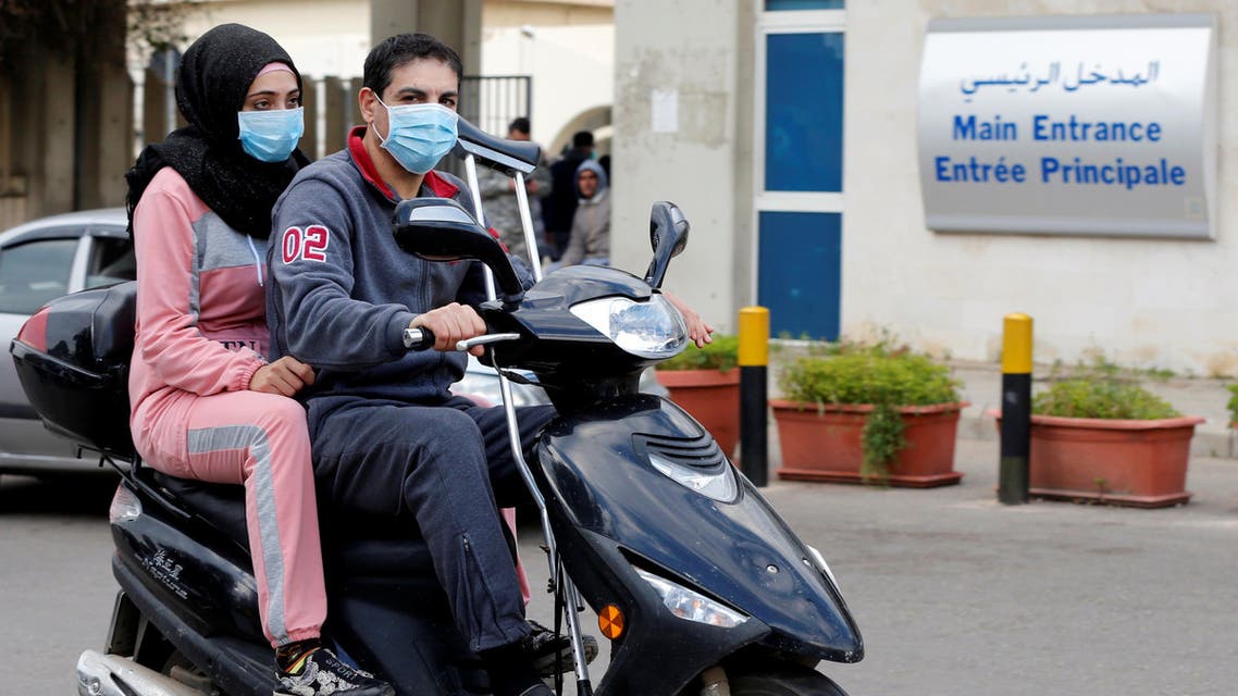 People wearing face masks ride on a motorbike outside Rafik Hariri hospital, where Lebanon's first coronavirus case is being quarantined, in Beirut, Lebanon. (Reuters)