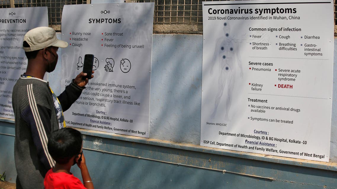 A man uses his mobile phone to take photographs of posters carrying messages on symptoms of coronavirus disease inside hospital premises in Kolkata, India. (Reuters)