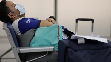A traveller wearing protective face mask takes a nap at Galeao International Airport in Rio de Janeiro, Brazil, after reports of the coronavirus March 6, 2020. (Reuters)