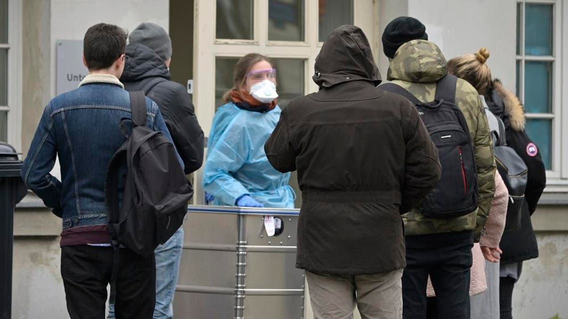 A medical employee talks with people waiting outside a new medical examination department in Berlin. (File photo: AFP)