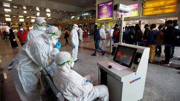 Medical staff in protective gear look at a screen while checking temperatures of passengers upon their arrival, following an outbreak of the coronavirus, at Najaf airport, in the holy city of Najaf, Iraq, February 26, 2020. (Reuters)
