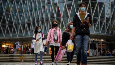 People wearing a face masks amid concerns about the spread of the COVID-19 novel coronavirus walk down a street in Hong Kong on March 7, 2020.