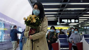 A woman wearing a mask holds a bunch of flower as a precaution against coronavirus at a subway station in Hong Kong on March 6, 2020. (AP)