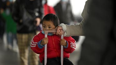 A child wearing a face mask arrives at Changsha railway station in Changsha, the capital of Hunan province on March 8, 2020. (AFP)