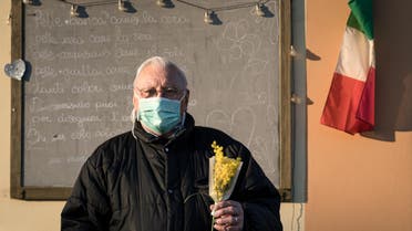 Life inside a red zone: A man wearing a protective mask holds a bouquet of flowers on a street outside on the 16th day of quarantine in San Fiorano, one of the 11 small towns in northern Italy that has been on lockdown since February. (Reuters)