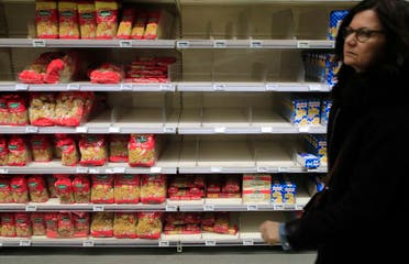 A woman walks past empty shelves at a supermarket in Paris, on March 9, 2020. Global share markets have plunged as panicked investors fled to the safety of bonds and the yen to hedge the economic trauma of the coronavirus. (AP)