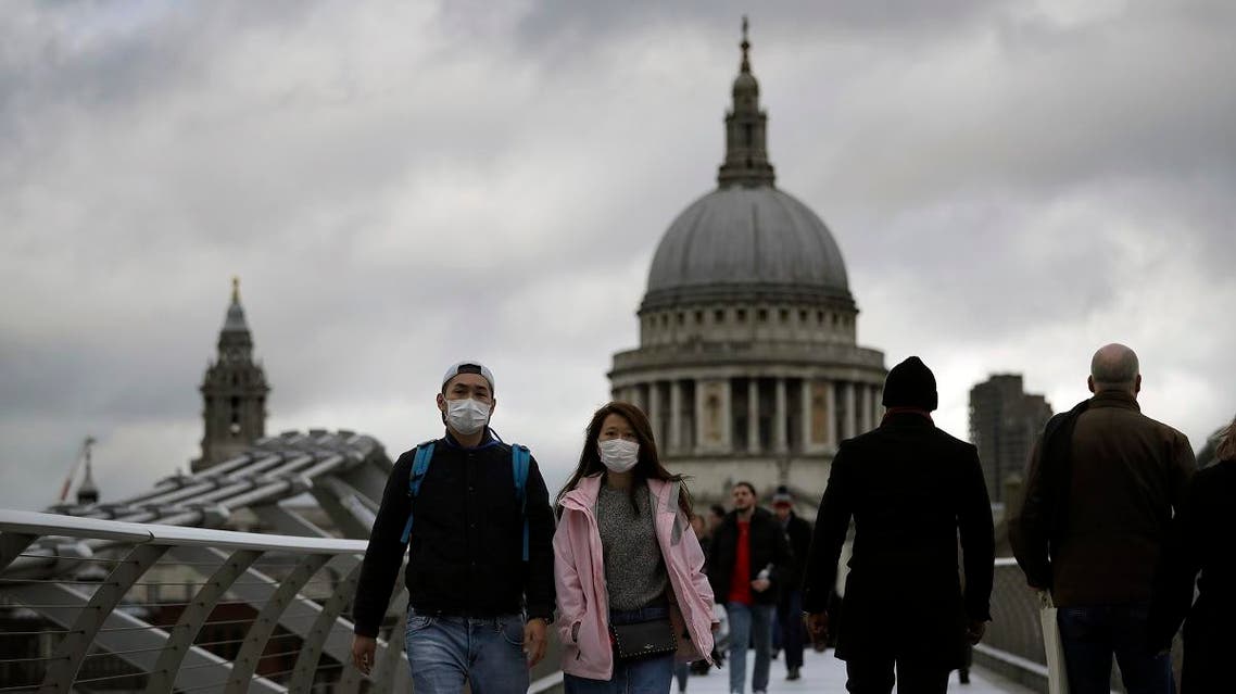 People wearing face masks walk across the Millennium footbridge backdropped by the dome of St Paul's Cathedral in London, Tuesday, March 10, 2020. (AP)