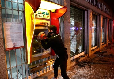 An anti-government protester destroys an ATM machine during ongoing protests against the Lebanese central bank's governor on Jan. 14, 2020 in Beirut. (AP)